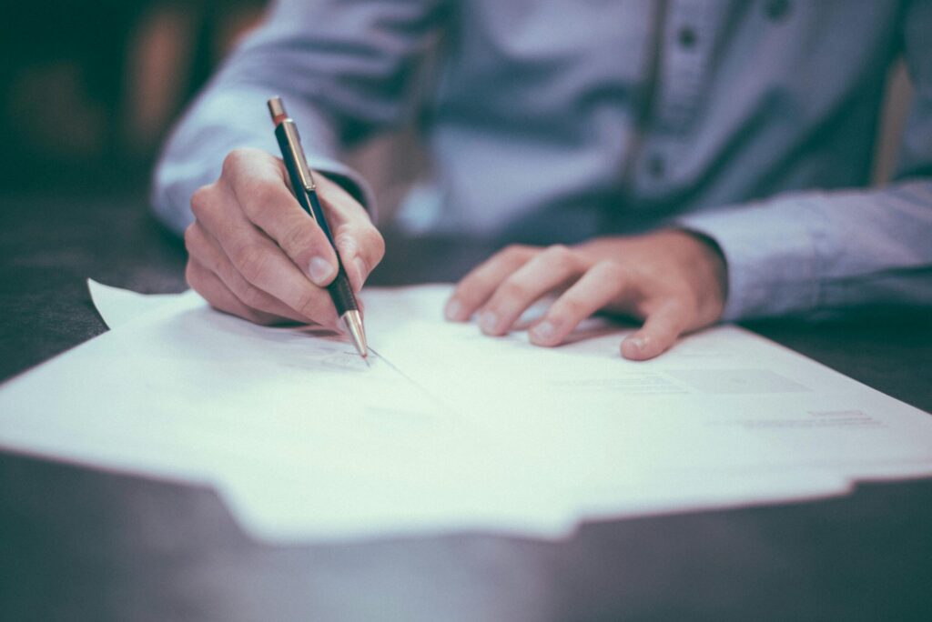 man writing on paper in business setting